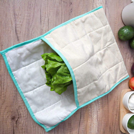 White quilted produce bag with turquoise trim with lettuce in it on a wood table