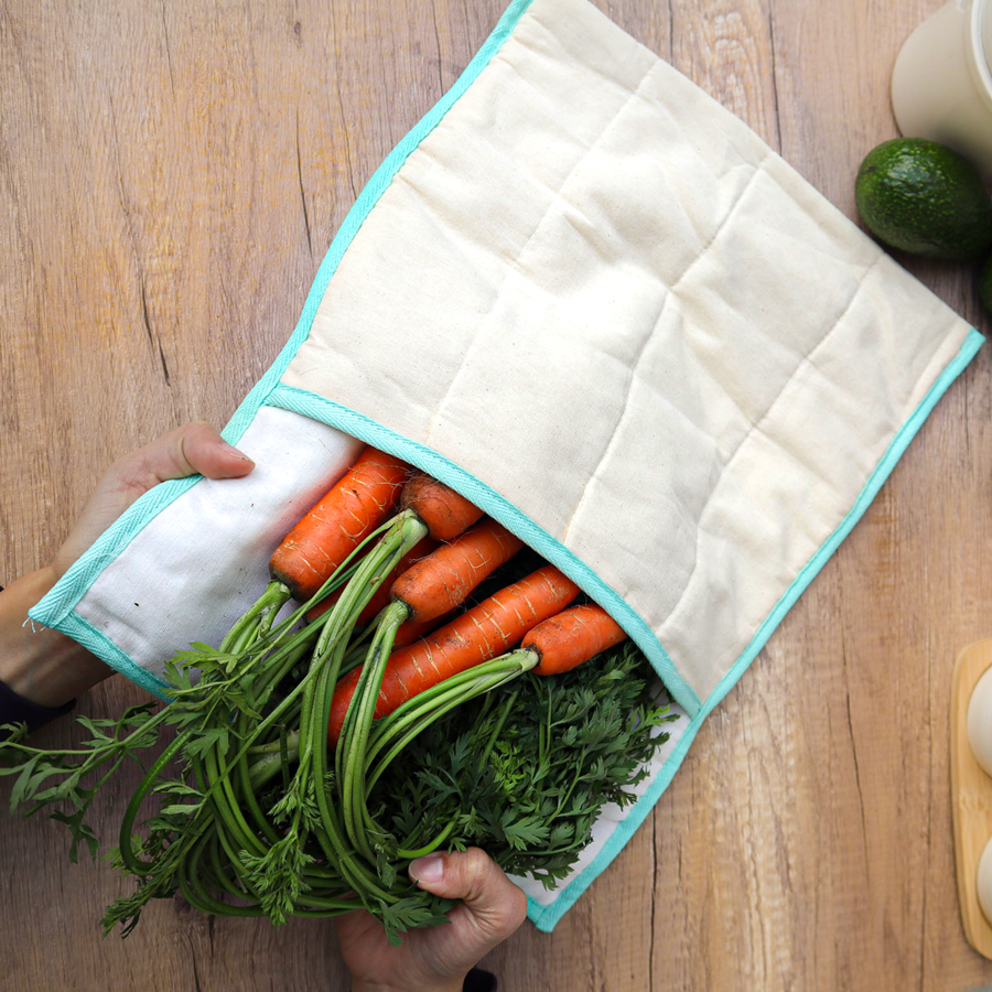 White quilted produce bag with turquoise trim with carrots in it on a wood table