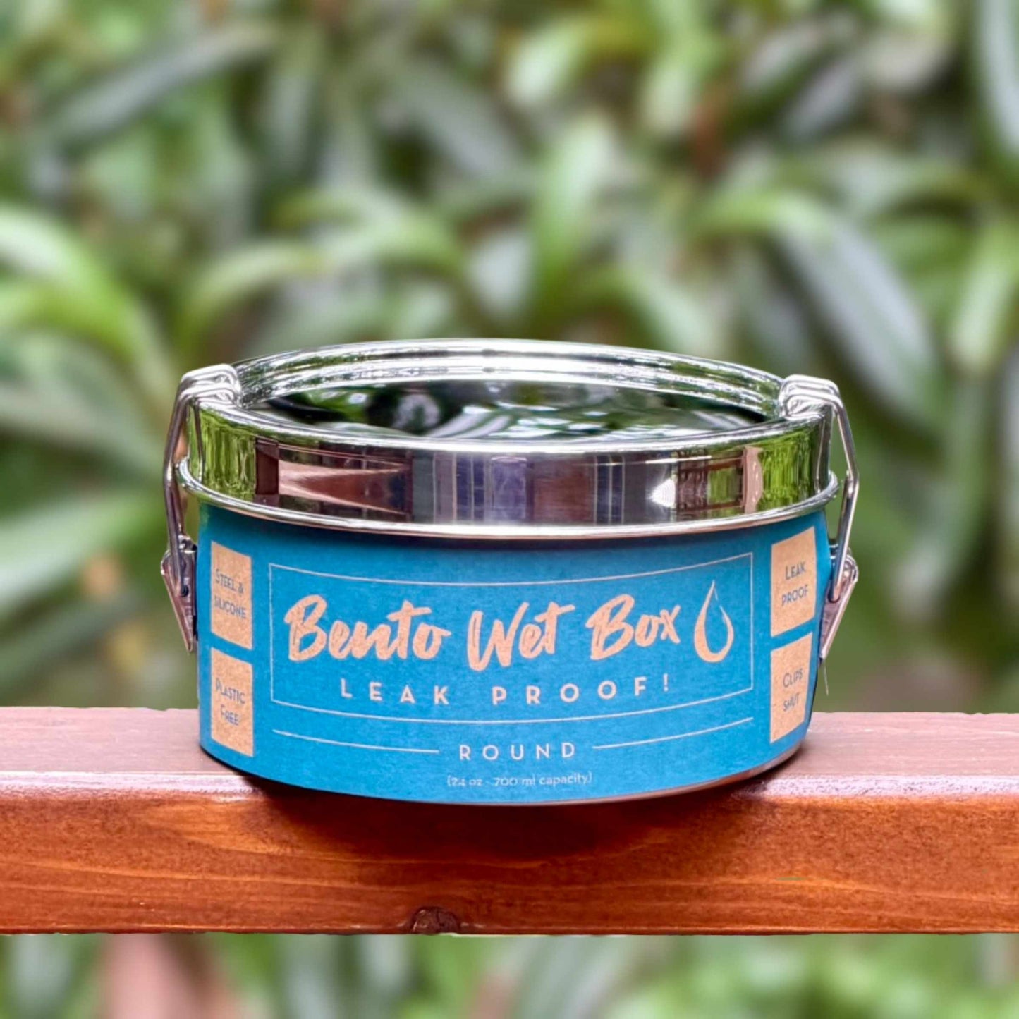 ECOlunchbox Bento Wet Box Round leakproof stainless steel container wrapped in its blue paper product label outdoors.