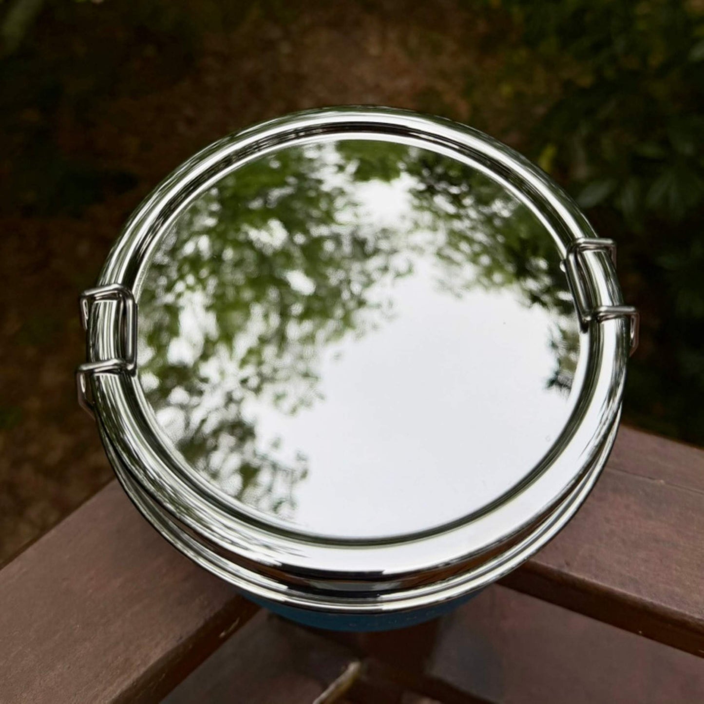 Top view of ECOlunchbox Bento Wet Box Round showing highly reflective polished stainless steel lid with locking latches.