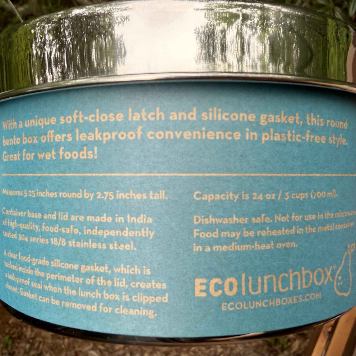 Close-up of ECOlunchbox Bento Wet Box Round packaging label detailing 18/8 stainless steel material, dimensions, and dishwasher safe instructions.