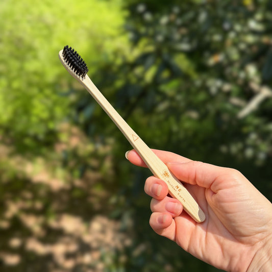 Bamboo charcoal toothbrush with castor oil bristles and Me Mother Earth logo