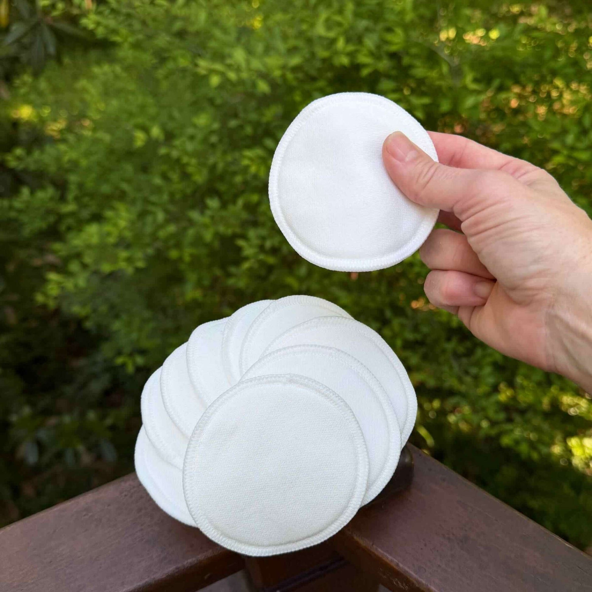 white cotton pad being held above a stack of white pads