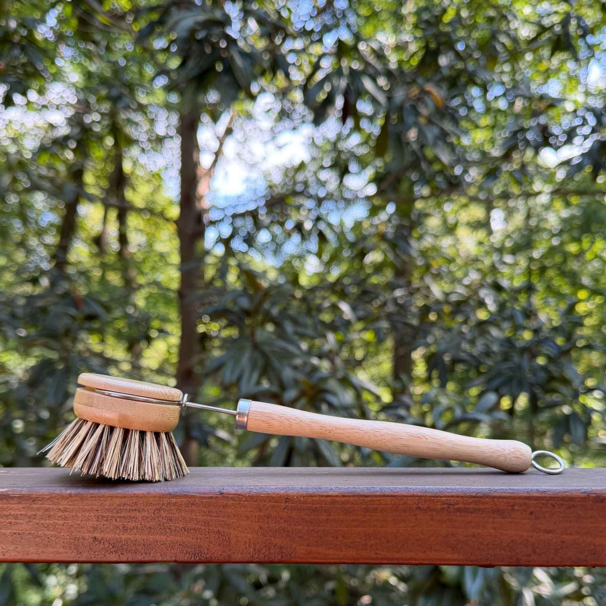 Firmer sisal and palm bristle pot scrubber brush on a wood railing outside