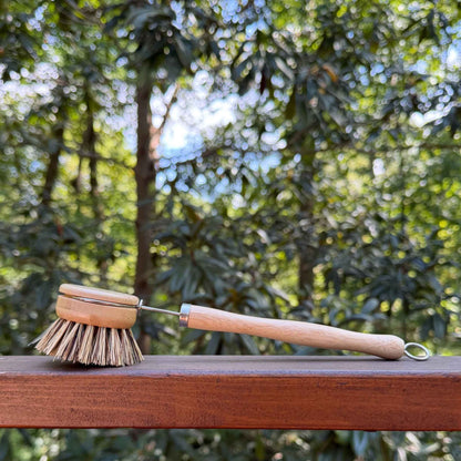Firmer sisal and palm bristle pot scrubber brush on a wood railing outside