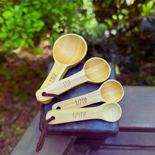 set of four wood measuring spoons with measurement markings on their handles sitting on a balcony above trees