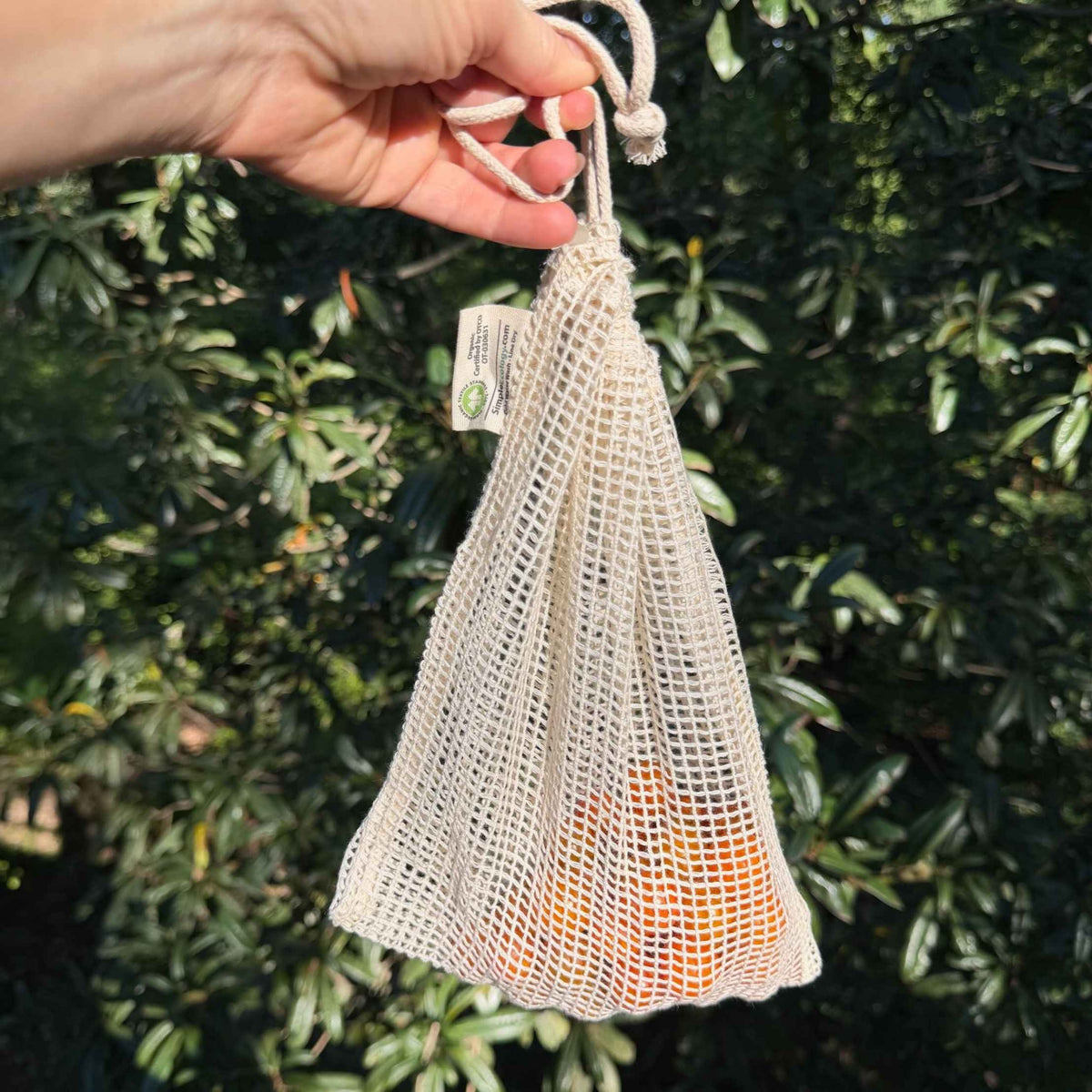 Organic cotton produce bag holding fresh vegetables, plastic-free grocery bag