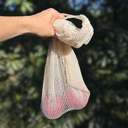 Organic cotton produce bag holding fresh apples, plastic-free grocery bag