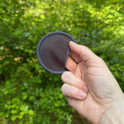fingers in a bamboo charcoal round's pocket with green trees in background