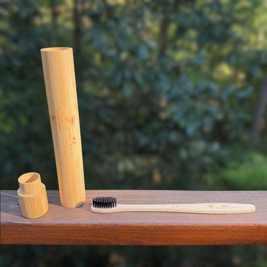 Bamboo toothbrush travel case, cap, and unwrapped bamboo toothbrush with black charcoal bristles on a railing