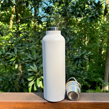 White insulated stainless steel water bottle sitting open next to its bamboo lid to show the metal underside threads and seal.