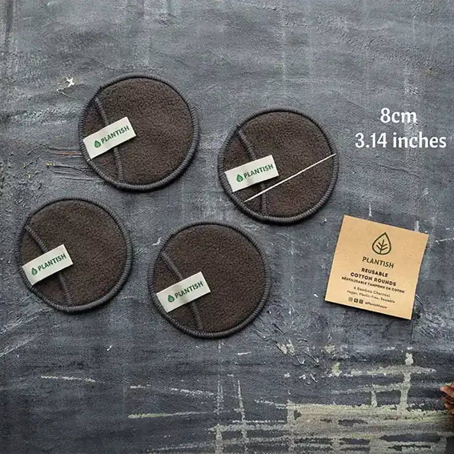 Four black charcoal makeup rounds on a gray table with Plantish labels on them