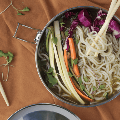 ECOlunchbox Bento Wet Box Round stainless steel container filled with noodles and veggies and chopsticks sticking out